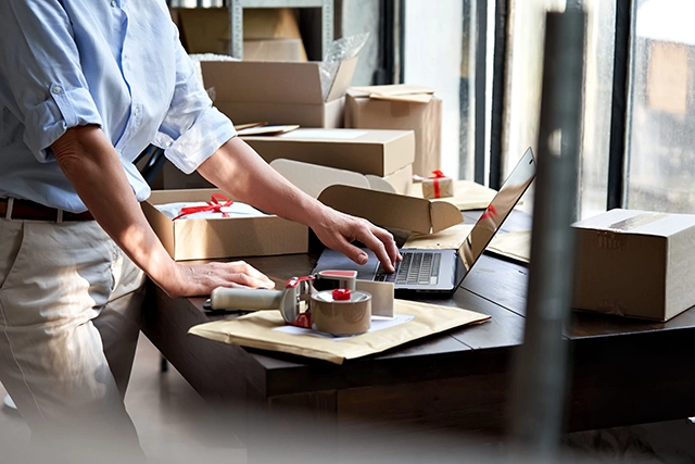 Business professional packing orders for shipping, symbolizing the effective ecommerce solutions provided by partnering with Route, as featured in the press release.